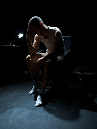 Artista musical sentado en una silla en una habitación ligeramente iluminada
